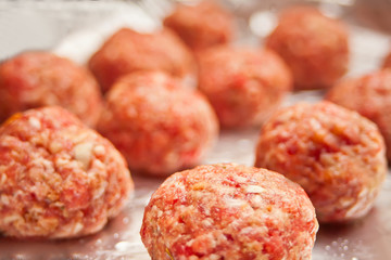 Row of raw meat balls on the foil.
