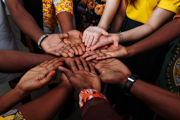 Hands of happy group of multinational African, latin american and european people which stay...