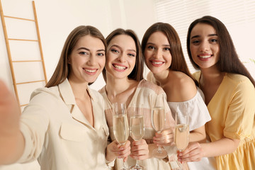 Beautiful young ladies with champagne taking selfie indoors. Woman's Day