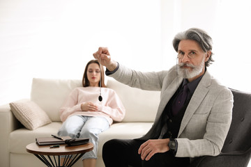 Psychotherapist using pendulum during hypnotherapy   session in office