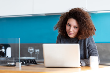 Young woman working on laptop in kitchen