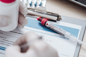 The technician fills the form after coronavirus test. Analysis of test tube with a sample. Tube of biological sample contaminated by Coronavirus. Medical exam. Specialist in a full protected suit.