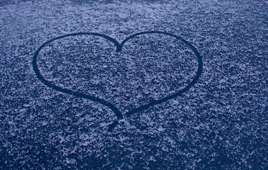 A heart drawn in fresh snow on a car window late at night at dusk. Concept of Valentine's day, love, winter