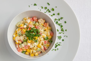 mayonnaise based salad with crab sticks, cucumber, sweet corn, bell pepper, and egg decorated with parsley