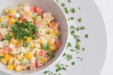 salad with sweet corn, crab sticks, and vegetables dressed with mayonnaise and decorated with finely chopped parsley 
