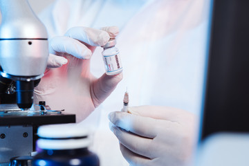 The microbiolog gets the vaccine into the syringe. Glass bottle in a doctor's hand. A bottle with a...