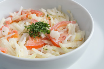 a bowl of white cabbage tomato salad with mayo decorated with dill