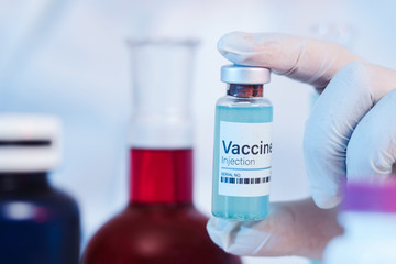 Glass medical bottle in a doctor's hand. A bottle with a cure holds a hand in silicone gloves in a...