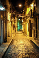 Rua muito antiga de Belém, PA, com pessoas distantes e postes com luz amarela - obrazy, fototapety, plakaty