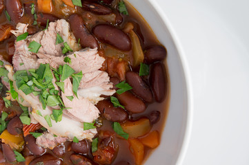 kidney beans stew with carrot, bell pepper, and tomatoes served with ham sprinkled with parsley