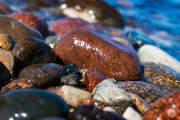 sea stones lying on the seashore, ocean in sunny weather washed by sea or ocean water
