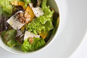lettuce salad with roasted pumpkin and walnuts, and feta sprinkled with black pepper and dressed with oil and vinegar