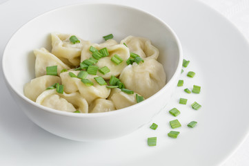 a bowl of pelmeni with green onion