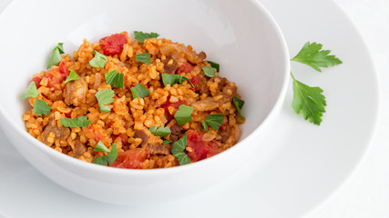 a bowl of bulgur pilaf with mutton decorated with parsley