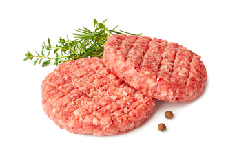 Two raw burger patties with thyme and reosemary on white