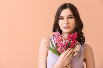 Beautiful young woman with hyacinth flowers on color background