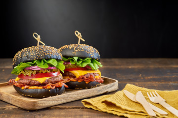 Two black hamburgers on dark wooden background