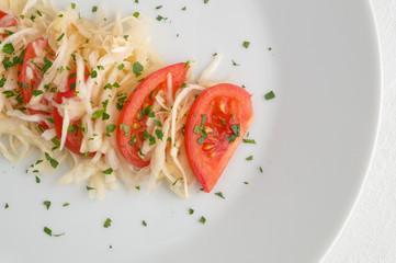 white cabbage salad with tomatoes dressed with oil and decorated with parsley