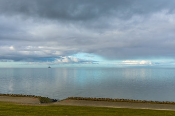 Very calm North Sea with reflections of the blue sky and an oil rig in the distance