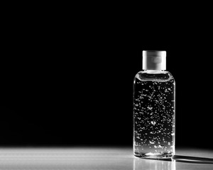 Transperent hand gel sanitizer bottle, black background. Bestseller on empty shelve sold out. Coronavirus pandemic hygiene shortage. Panic buying, deficit, speculation on high price, limited supply.