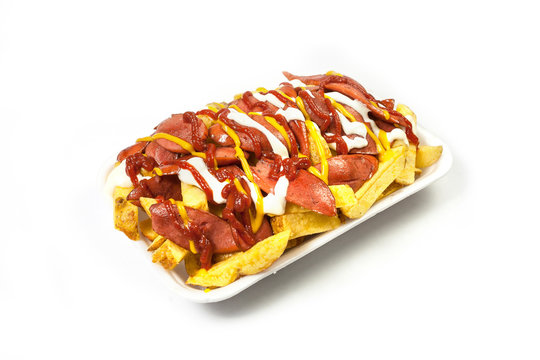 Peruvian street food:  Classic salchipapas or sausages and french fries  with ketchup, mustard, mayonnaise and chili peppers served on a white plate