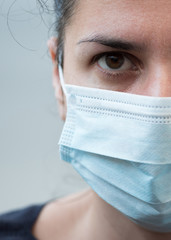 Woman wearing a face surgical mask on gray background. Selective focus. Flu, illness, pandemic concept