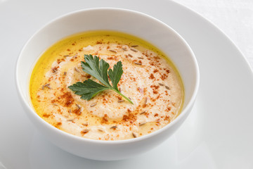 hummus sprinkled with paprika and zira decorated with parsley leaf 
