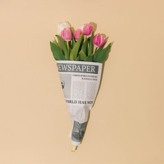 Spring tulips flowers wrapped in newspapers with Global Pandemic is over headline. Coronavirus...
