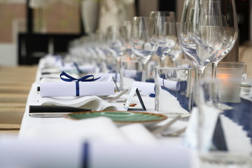 napkin with a blue ribbon and bow lying on a set dinner table with a little sign saying : love