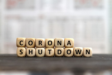 CORONA shutdown word built with cubes on a blurred business newspaper background