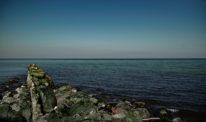 view of the rocky beach of the sea or ocean in sunny weather with clear blue sky