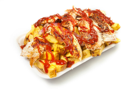 Peruvian street food:  Chicken salchipapas or pollo a la brasa slices  and french fries with ketchup served on a white plate