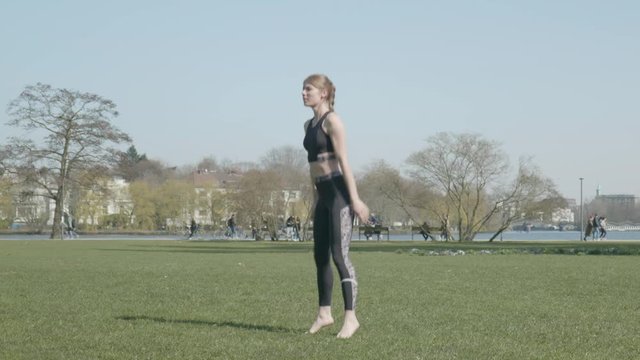 Fit woman doing outdoor workout jumping squats