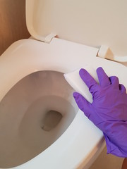 Closeup of lady wearing glove using sponge to clean toilet.  Hygiene concept.