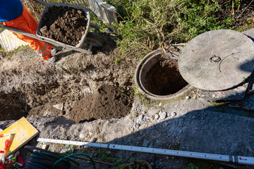 High angle view of laborer, pushing a wheelbarrow filled with heavy soil.