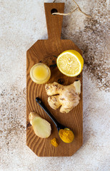 Immune boosters. Ginger, curcumin powder, lemon and honey on wooden board. Top view.