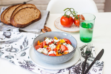 Fresh healthy salad with tomatoes, grilled pepper, cheese, pumpkin seeds and black sesame.
