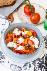 Fresh healthy salad with tomatoes, grilled pepper, cheese, pumpkin seeds and black sesame.
