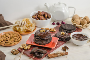 Vegan, vegetarian raw food healthy nut-banana chocolate brownie pastry on a white wooden background. Homemade from dates, walnuts, almonds and chocolate.