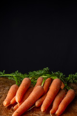 Top view of carrots, on weathered wooden table, with black background, vertical, with copy space