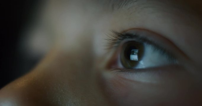 Macro  shot of child eyes while using a tablet, smartphone or computer. Concept: future of web technology, video technology, connections and vision of the future of children with the web. 