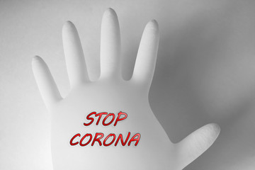 Medical glove on a white background with the text STOP CORONA. Pandemic, coronavirus.