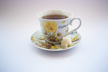 Cup with tea and sugar cubes on a white background