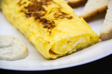 Amazing breakfast with tasty omelet, tomatoes, cheese, bread and sauce on the white plate. Delicious omelet made like rolle, other ingredients. Tasty and diet food. Healthy meal for breakfast or lunch