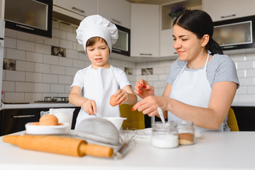 Young mother and her little son baking cookies together at home kitchen