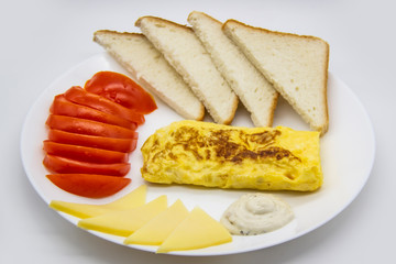 Amazing breakfast with tasty omelet, tomatoes, cheese, bread and sauce on the white plate. Delicious omelet made like rolle, other ingredients. Tasty and diet food. Healthy meal for breakfast or lunch