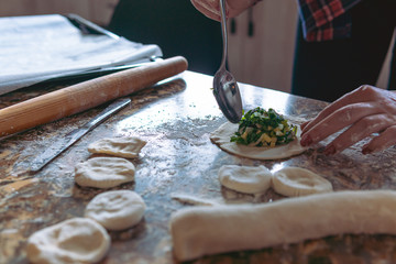 Woman cooking pies, also known as somsa, at home, making food from dough 