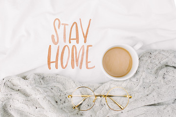 Stay Home, quarantine. Cup of coffee on bed with warm plaid. Copy space. Flat lay, top view