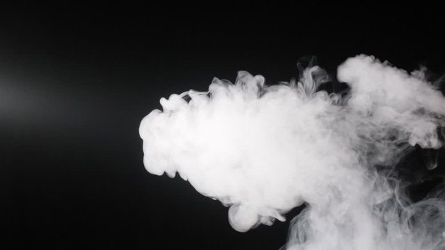 A man smokes a vape on a black background close-up. Slow motion