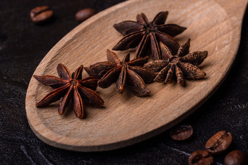 Anis on a wooden spoon on a concrete background with coffe grains